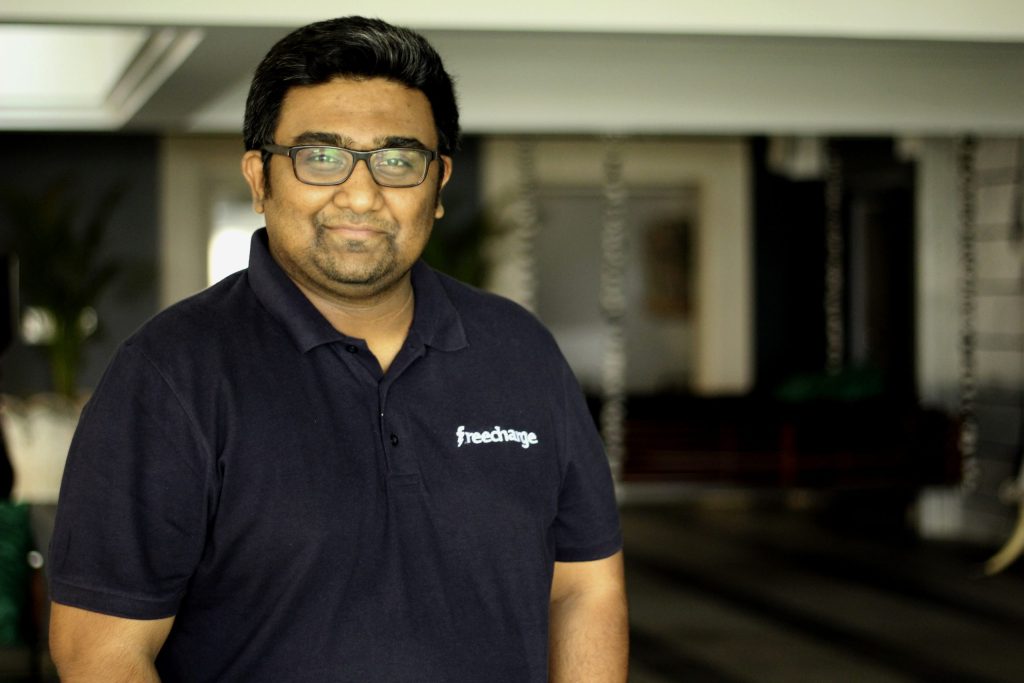 Kunal Shah in glasses and a dark FreeCharge polo shirt, smiling