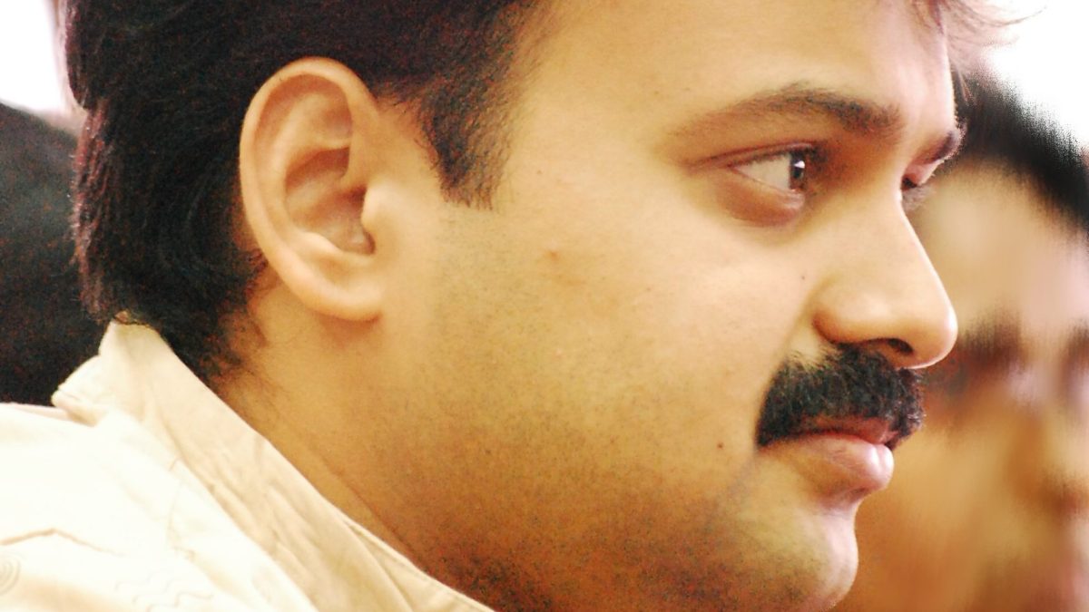 Kunchacko Boban with a moustache, in a cream shirt, looking to one side