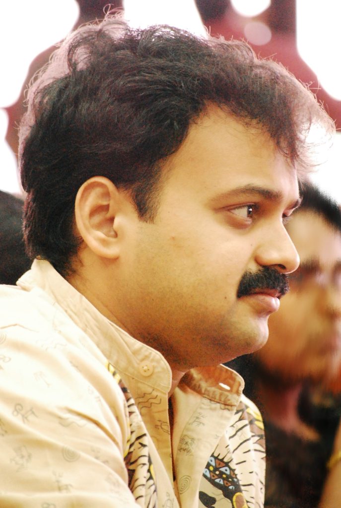 Kunchacko Boban with a moustache, in a cream shirt, looking to one side