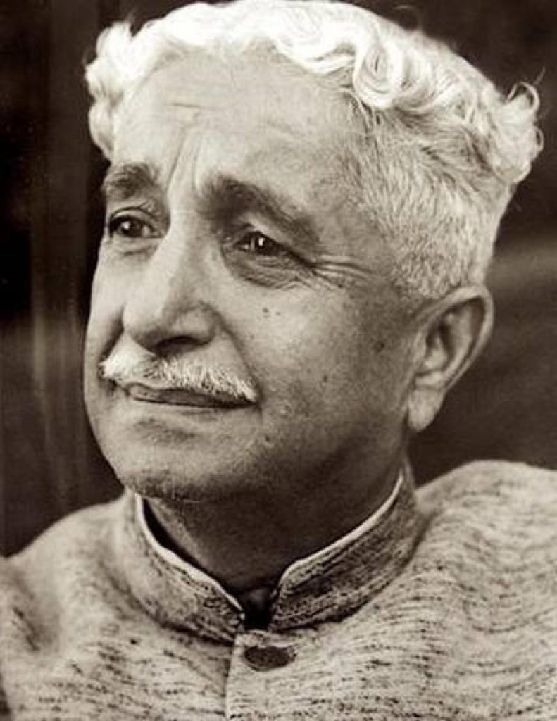 A black-and-white portrait of Kuvempu with wavy white hair and a moustache, looking to one side