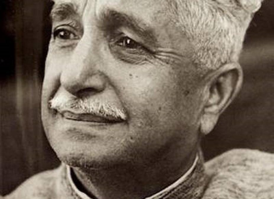 A black-and-white portrait of Kuvempu with wavy white hair and a moustache, looking to one side