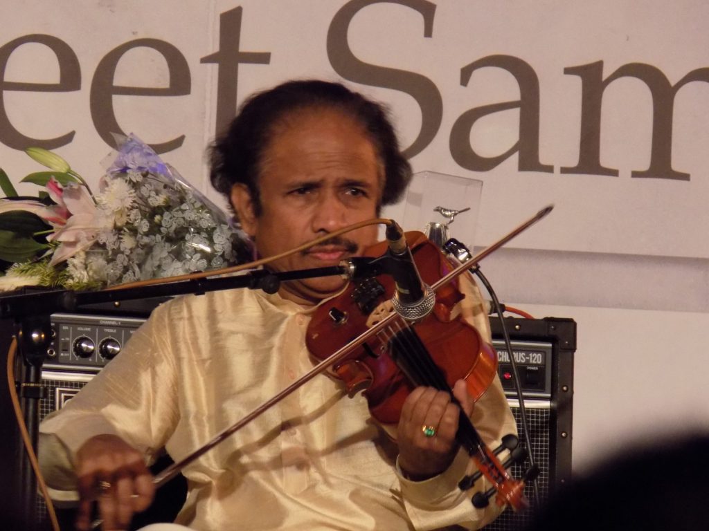 L. Subramaniam in a cream kurta playing the violin on stage