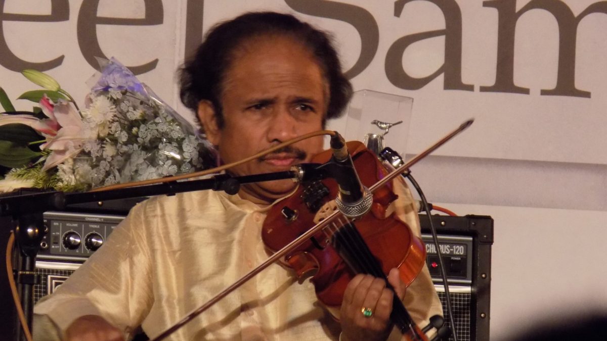 L. Subramaniam in a cream kurta playing the violin on stage