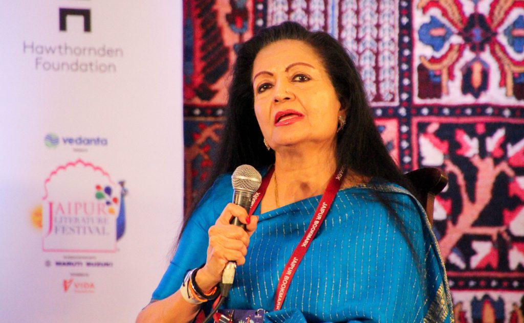 Lakshmi Puri in a blue sari speaking into a microphone at a festival session