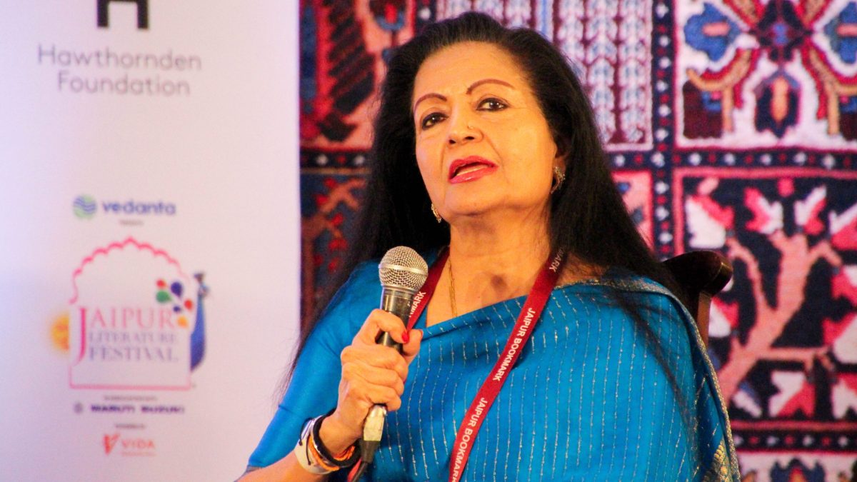 Lakshmi Puri in a blue sari speaking into a microphone at a festival session