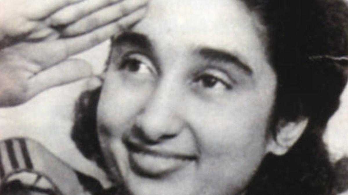 Black-and-white close-up of a young Lakshmi Sahgal smiling and saluting