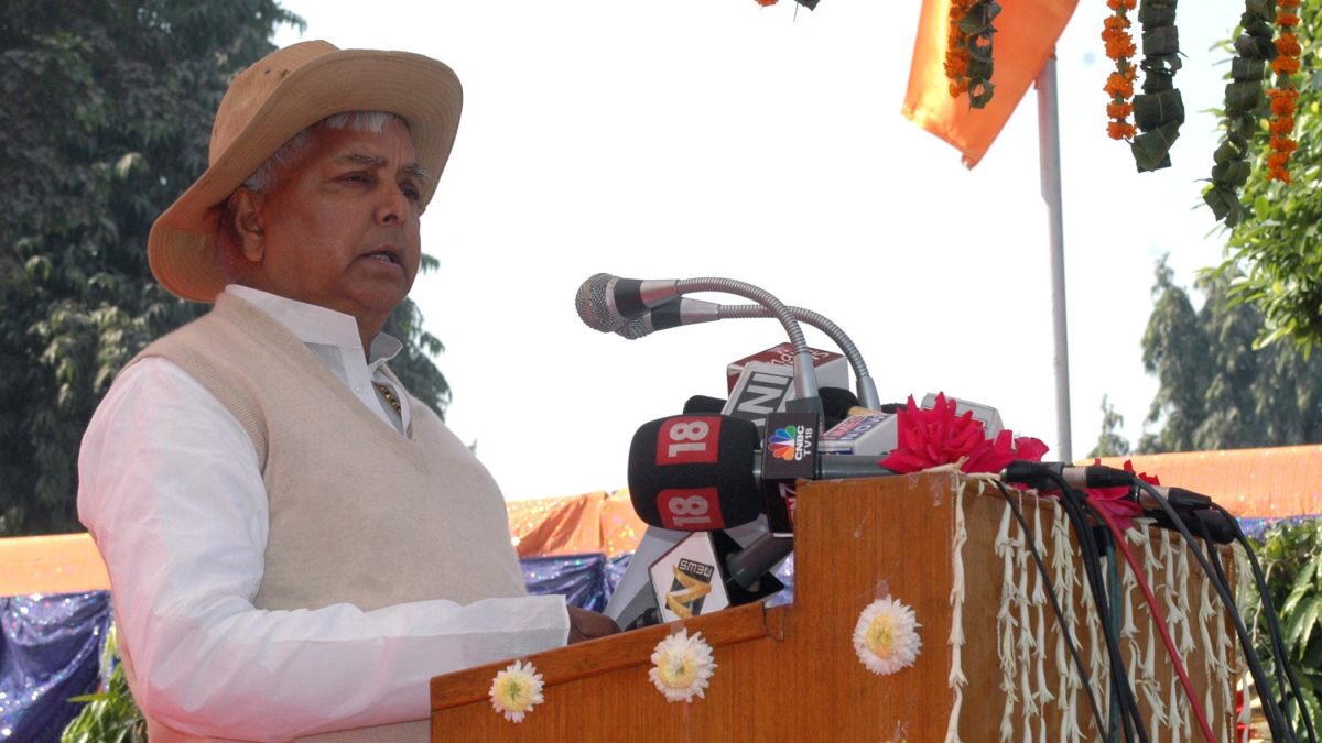 Lalu Prasad Yadav in a hat and waistcoat speaking at a decorated lectern