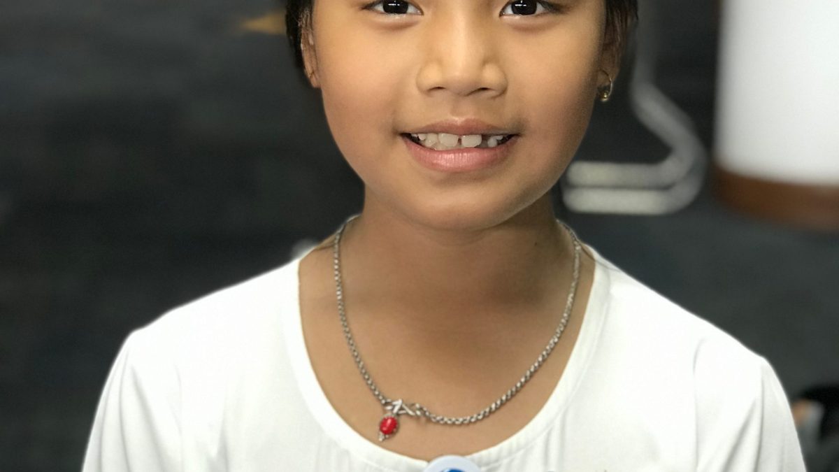 Licypriya Kangujam, aged seven, smiling in a white top with conference badges