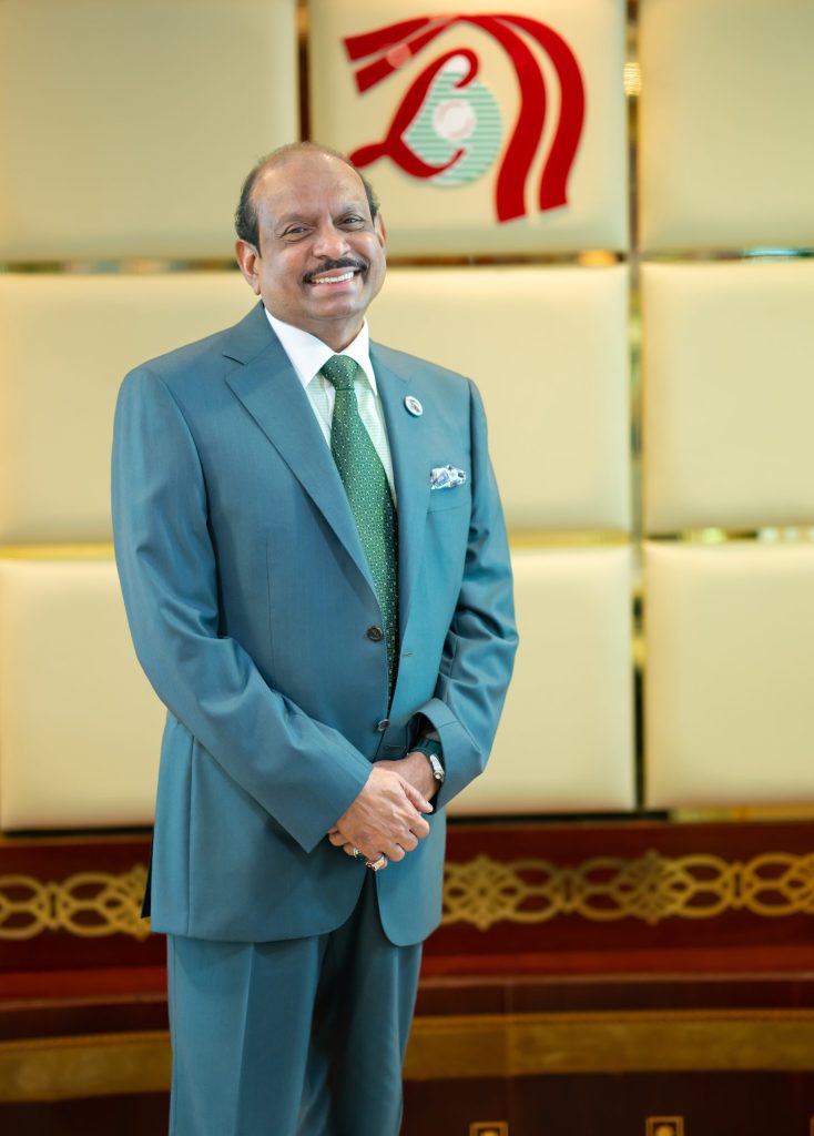 M. A. Yusuff Ali standing in a green suit in the lobby of his office