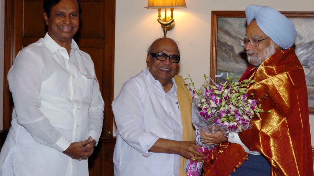 M. Karunanidhi in dark glasses and a yellow shawl greeting Prime Minister Manmohan Singh with flowers