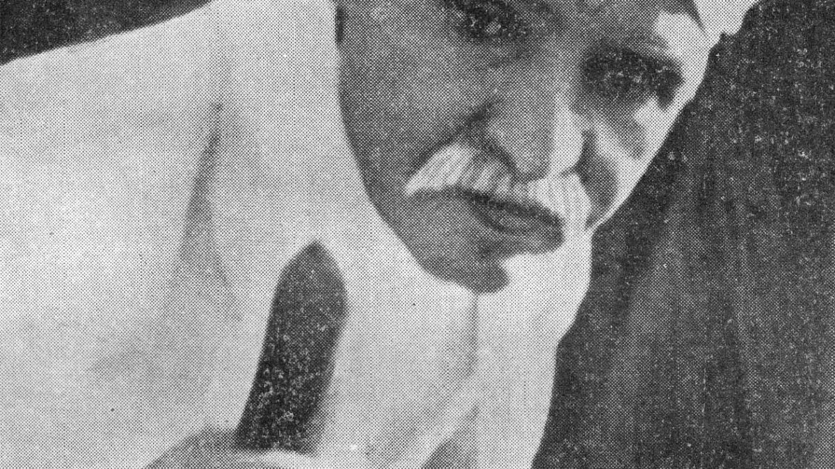 Old photograph of Madan Mohan Malaviya in a white turban and shawl, holding a staff