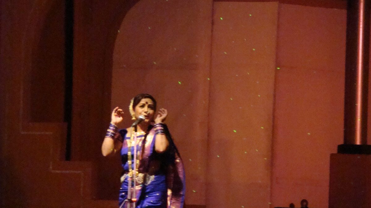A woman in a blue sari performing Lavani on stage