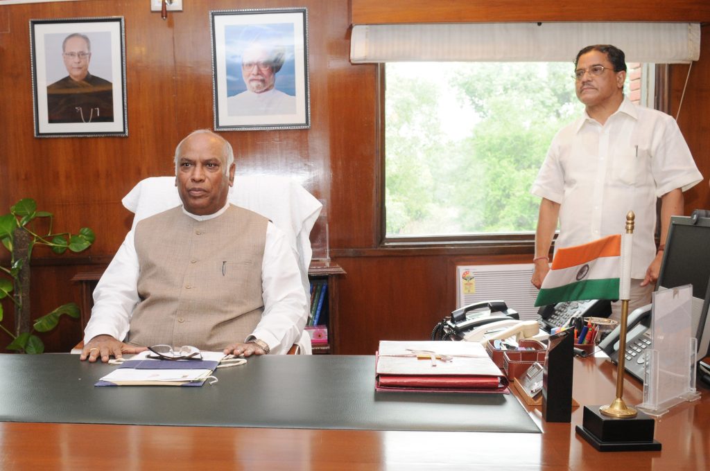 Mallikarjun Kharge in a white kurta and waistcoat seated at his desk