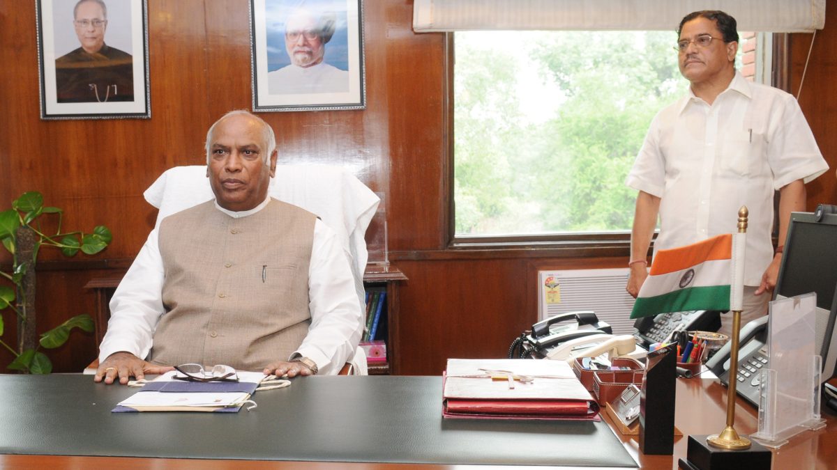 Mallikarjun Kharge in a white kurta and waistcoat seated at his desk