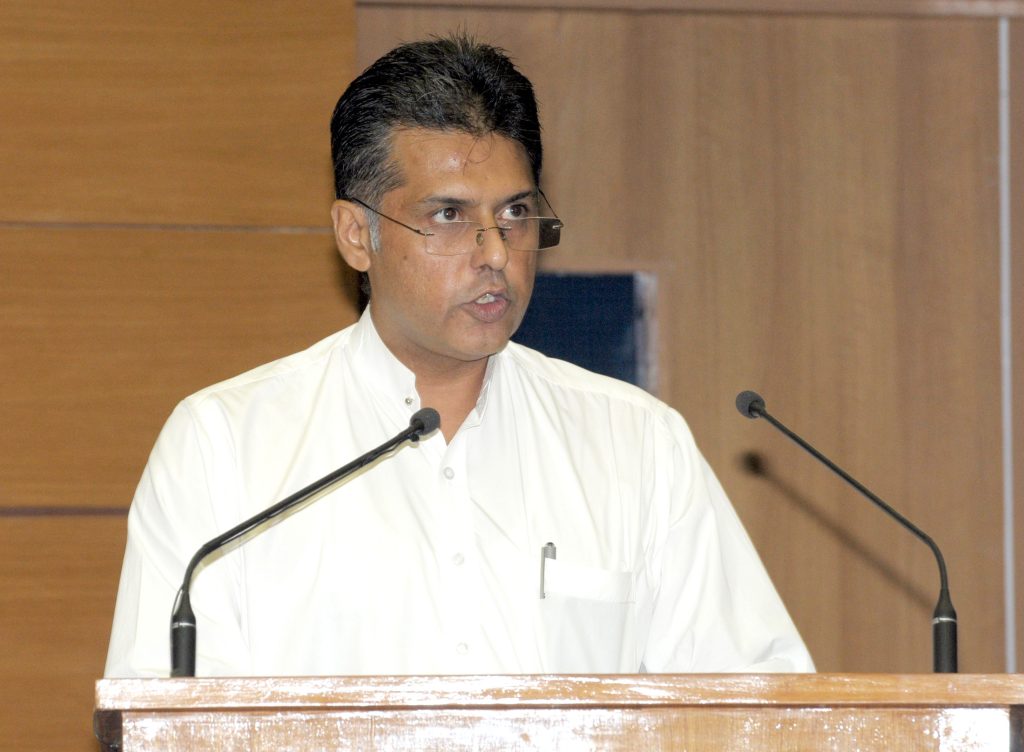 Manish Tewari in a white kurta speaking at lectern microphones