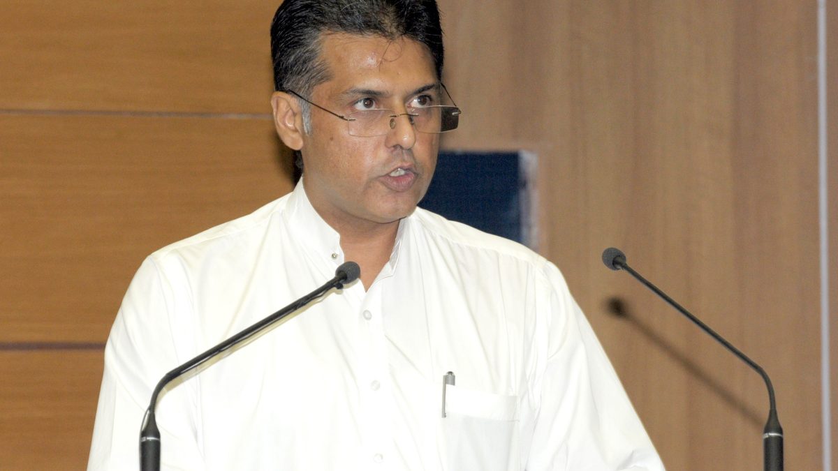 Manish Tewari in a white kurta speaking at lectern microphones