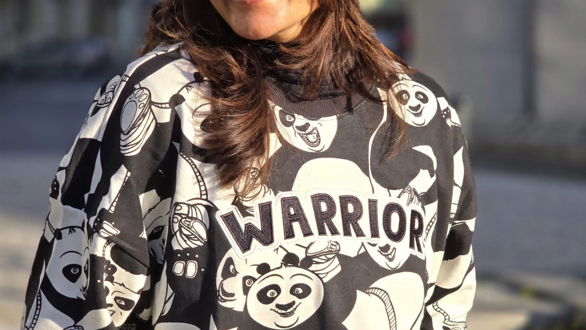 Manju Warrier smiling, wearing headphones around her neck and a printed sweatshirt