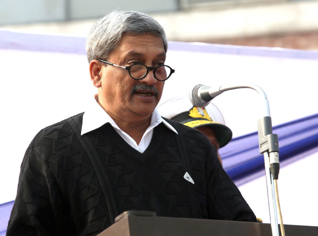 Manohar Parrikar in glasses and a dark jacket speaking at a lectern