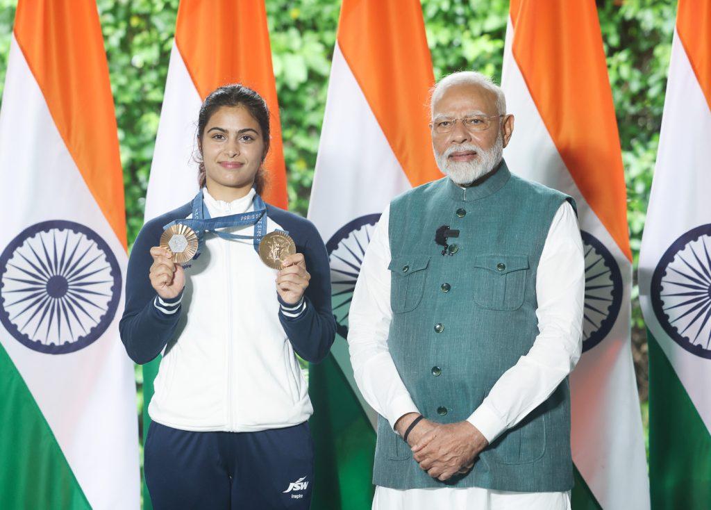 Manu Bhaker holding her two Paris Olympic bronze medals beside Prime Minister Narendra Modi