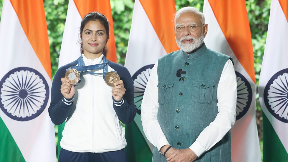 Manu Bhaker holding her two Paris Olympic bronze medals beside Prime Minister Narendra Modi