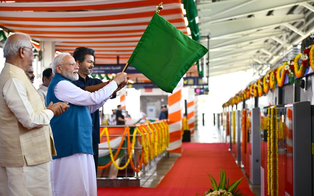 Prime Minister Narendra Modi waving a green flag to flag off a Chennai Metro train, with officials beside him