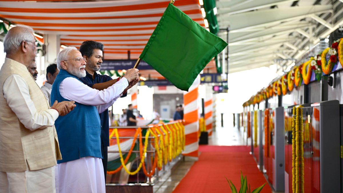 Prime Minister Narendra Modi waving a green flag to flag off a Chennai Metro train, with officials beside him