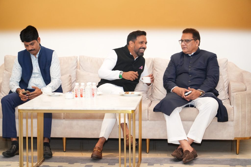 Mohammad Azharuddin in a dark kurta seated on a sofa with two other men