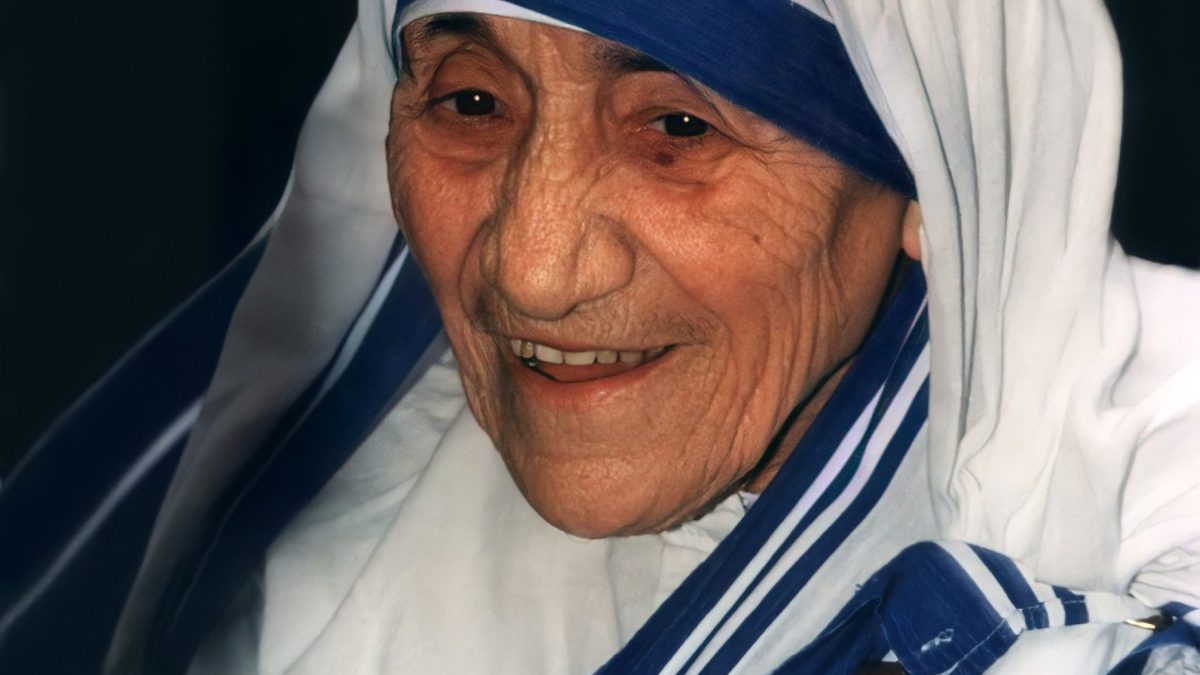 Mother Teresa smiling, in her white sari with blue borders