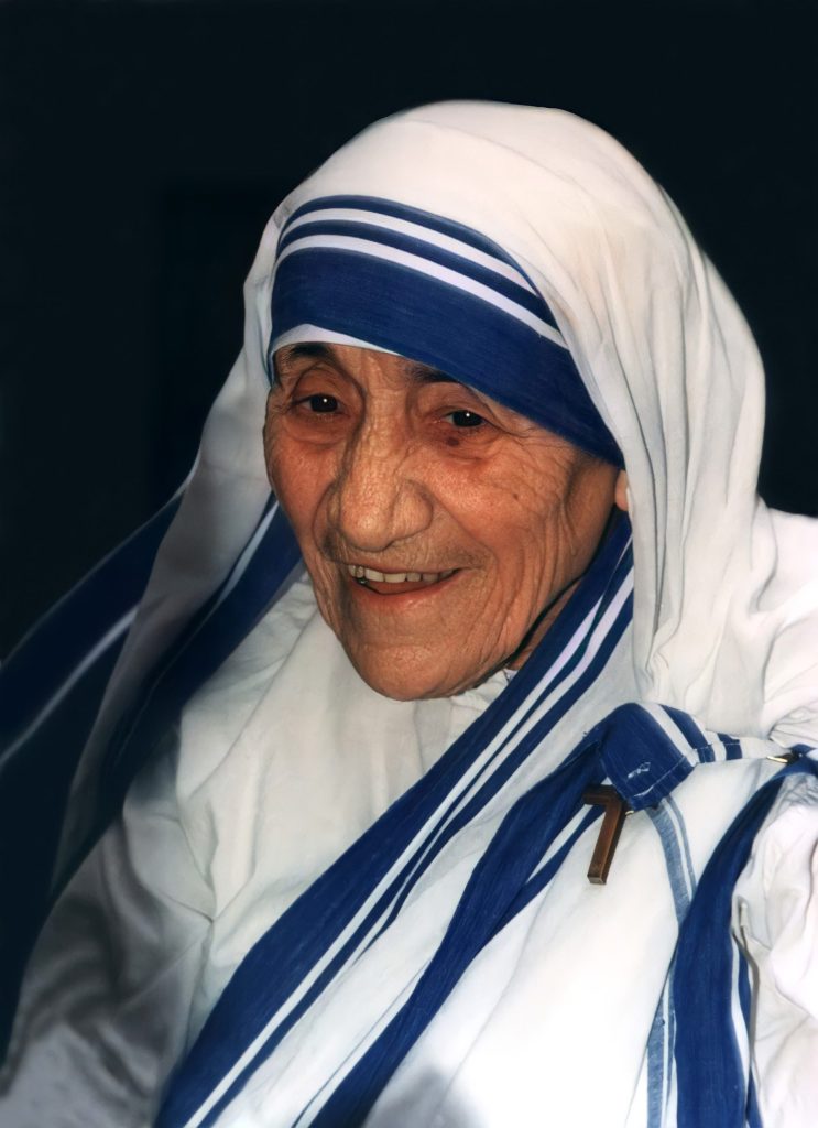 Mother Teresa smiling, in her white sari with blue borders