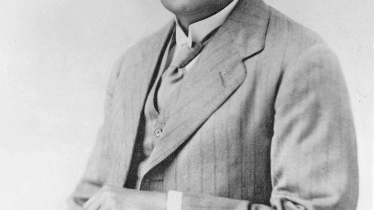 Black-and-white photograph of Motilal Nehru seated in a three-piece suit, holding a book