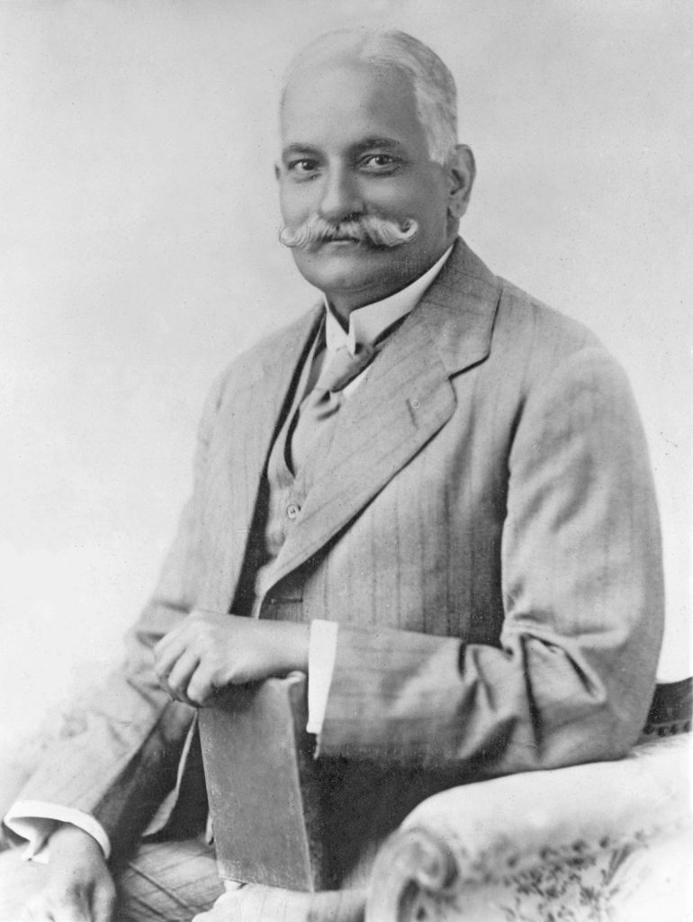 Black-and-white photograph of Motilal Nehru seated in a three-piece suit, holding a book