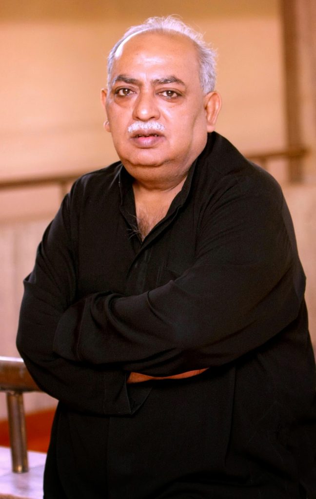 Munawwar Rana in a black kurta standing with his arms folded