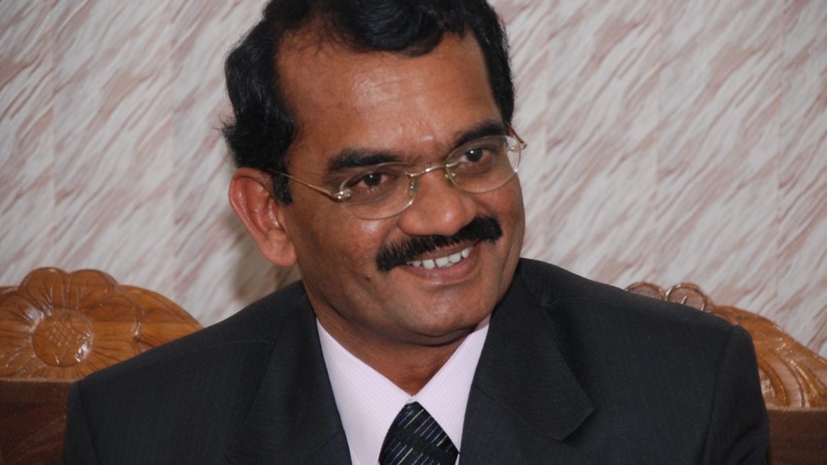 Mylswamy Annadurai in a dark suit, smiling, seated on a sofa