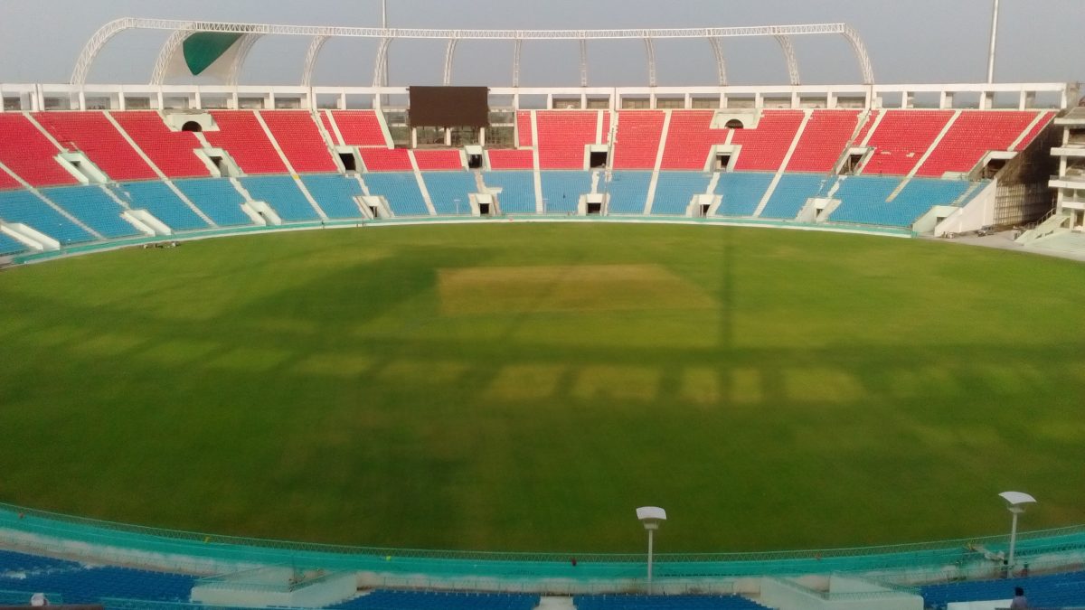 The green outfield and red and blue stands of the Ekana Cricket Stadium in Lucknow