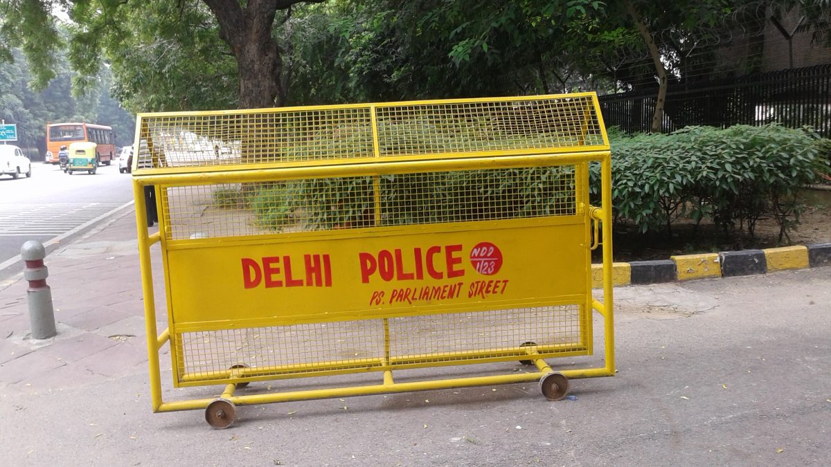 A yellow Delhi Police barricade standing on a road in New Delhi