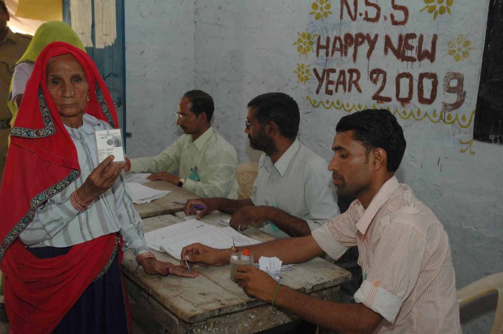 An elderly woman voter showing her voter identity card at a polling booth