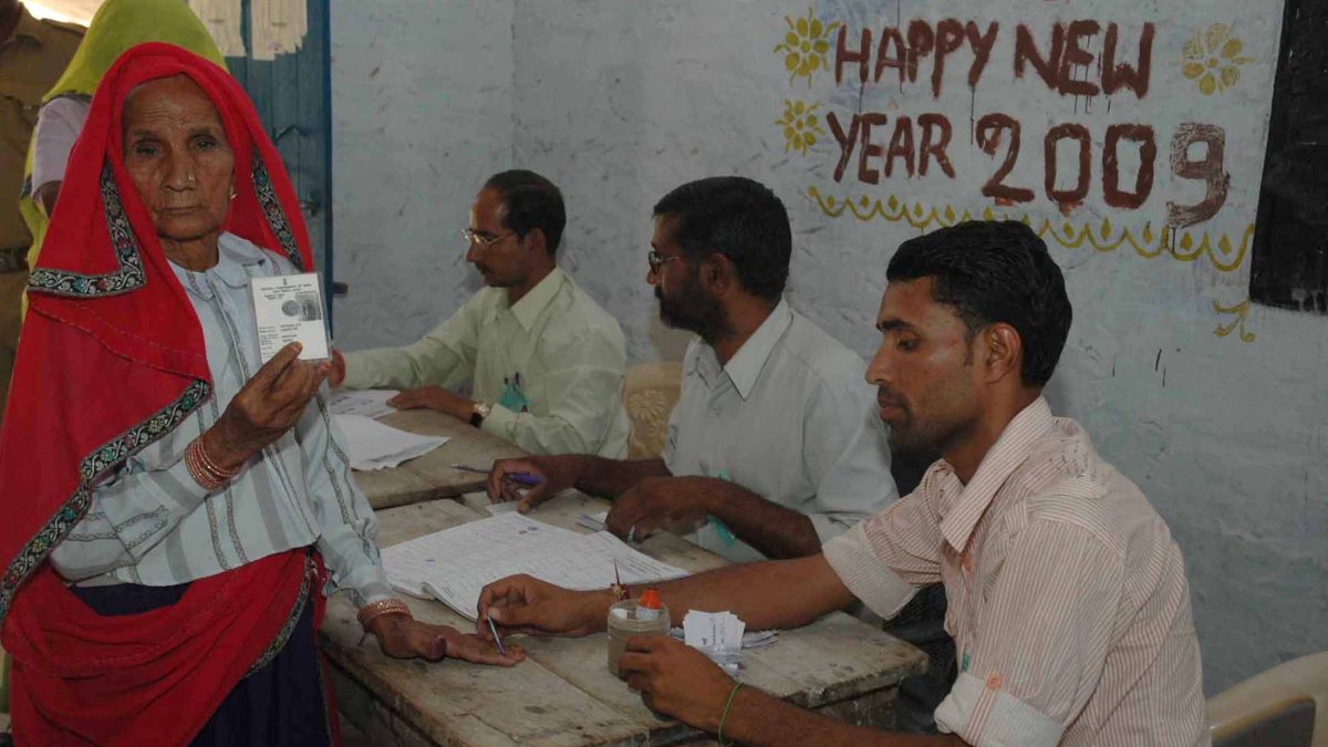 An elderly woman voter showing her voter identity card at a polling booth