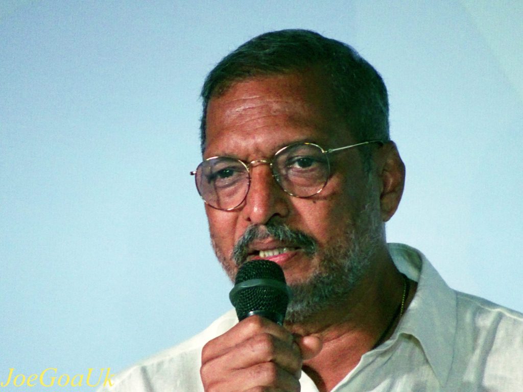 Nana Patekar in glasses and a white shirt speaking into a microphone