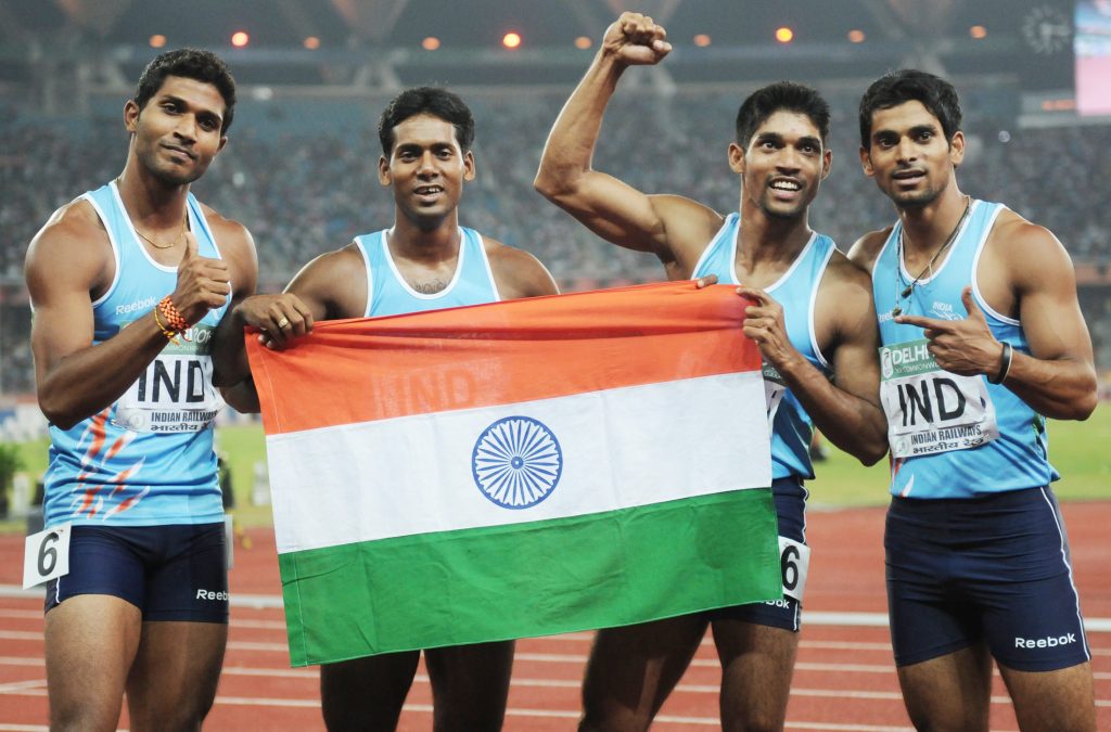 Indian sprinters holding the national flag on the track