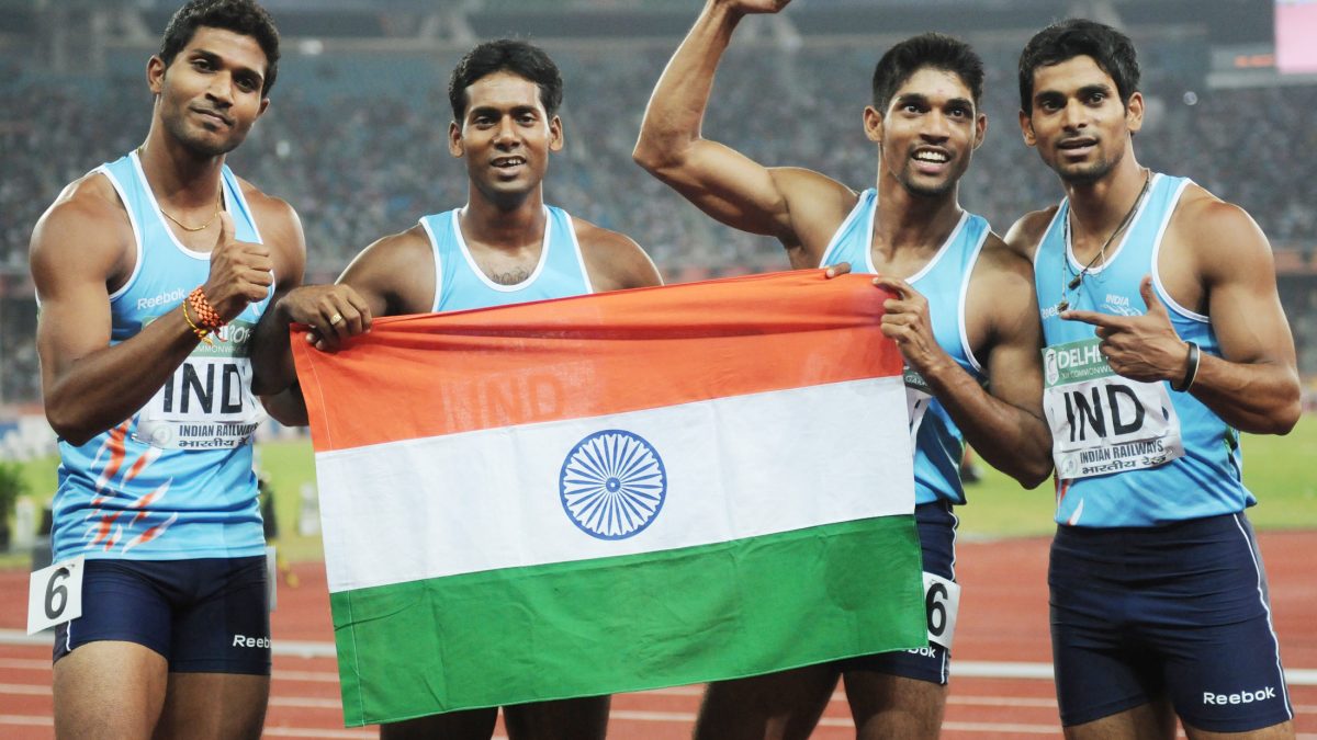 Indian sprinters holding the national flag on the track