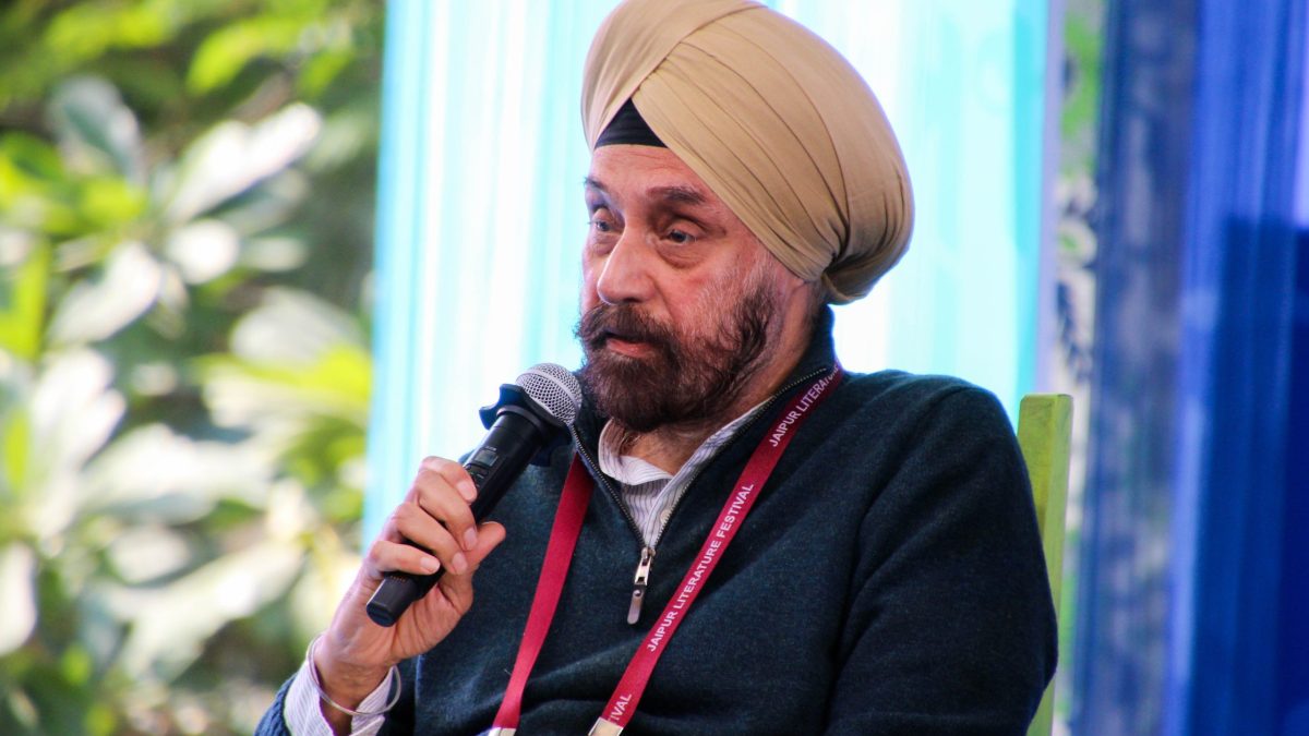 Navtej Sarna in a tan turban and dark jacket speaking into a microphone