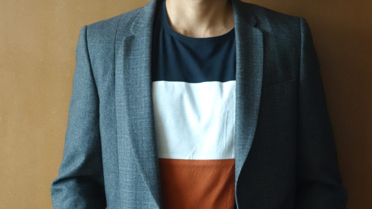 Nikhil Kamath smiling in a grey blazer and striped T-shirt