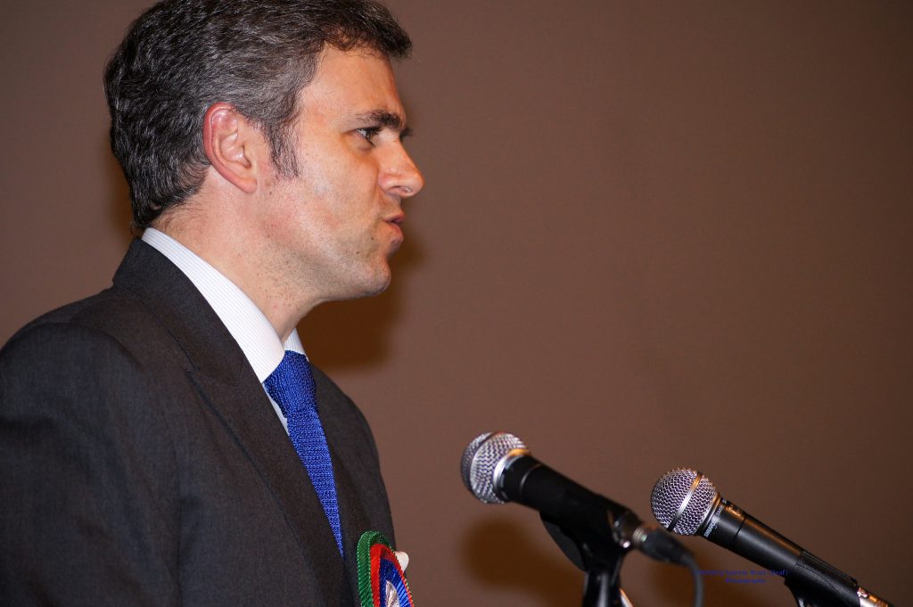 Omar Abdullah speaking at a podium with two microphones