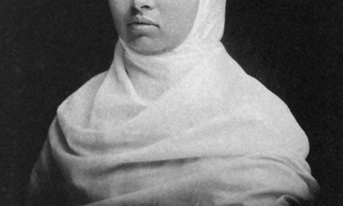 Black-and-white portrait of Pandita Ramabai with a white shawl over her head and her signature below