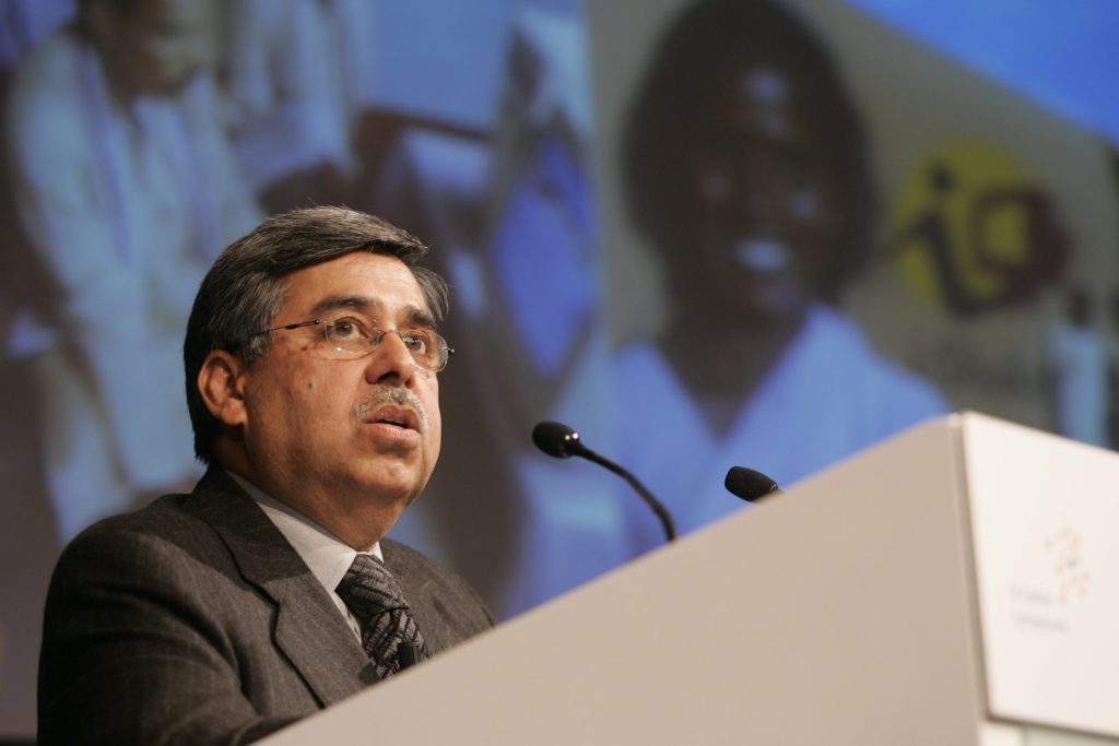 Pawan Munjal in glasses and a dark suit speaking at a lectern