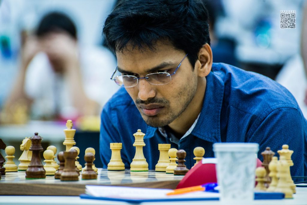 Pentala Harikrishna in glasses and a blue shirt concentrating at a chessboard