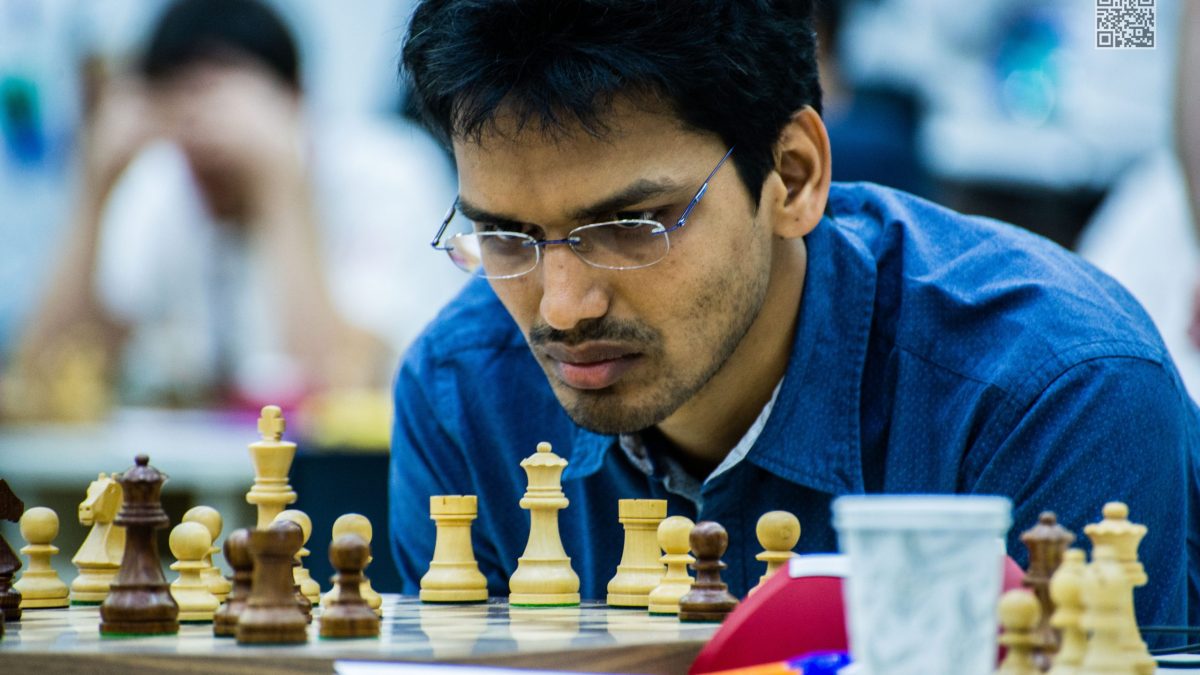 Pentala Harikrishna in glasses and a blue shirt concentrating at a chessboard
