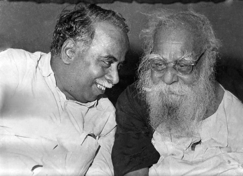 Black-and-white photograph of the white-bearded Periyar, right, in conversation with C. N. Annadurai