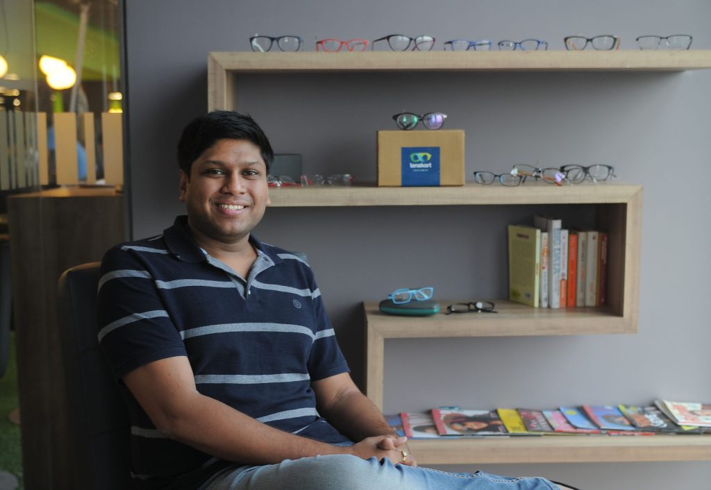 Peyush Bansal in a striped polo shirt seated in an office, smiling