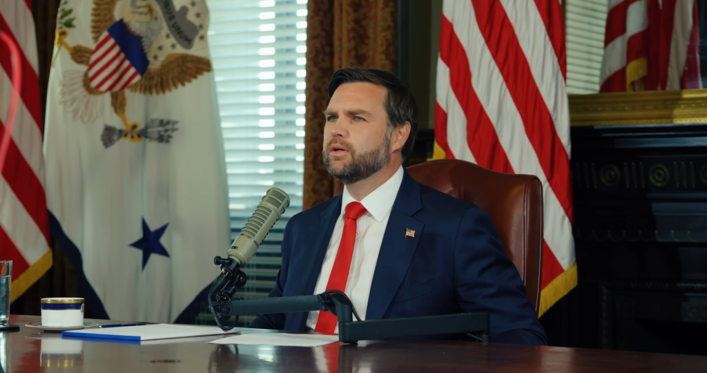US Vice President JD Vance seated at a desk in front of flags